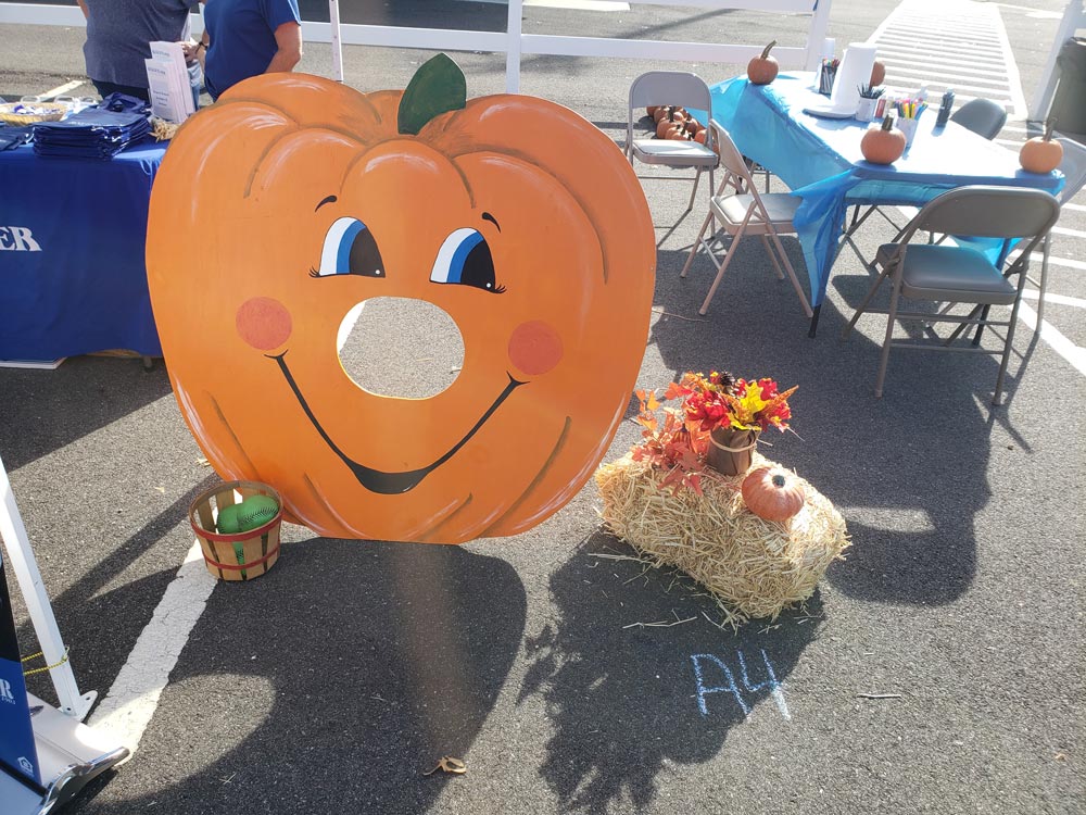 Cutout of pumpkin standing up smiling next to flowers