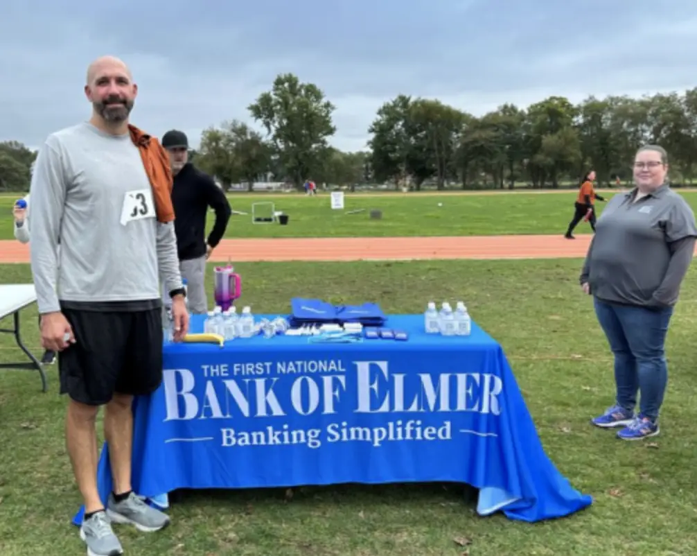Man and woman standing outside with Bank of Elmer table in field