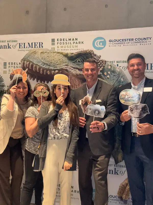 Group of bank employees having fun in front of dinosaur display