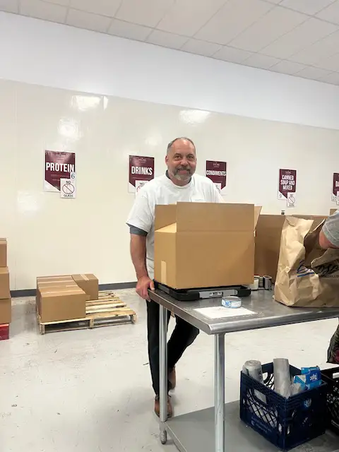 Anthony standing by a packed box