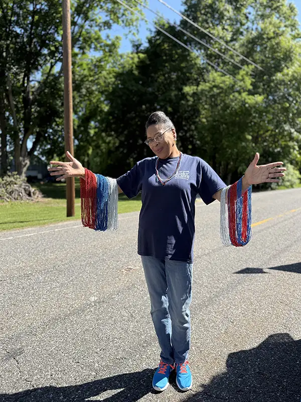 Bank employee standing outside with red, white, and blue beaded necklaces.