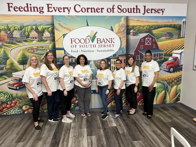 Volunteers posing in front of the Food Bank wall mural