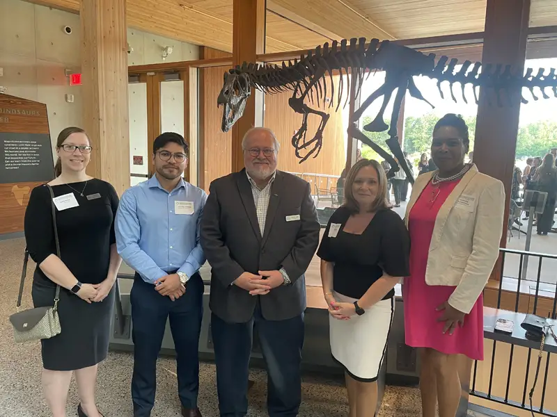 Attendees to meeting posing in front of dinosaur skeleton