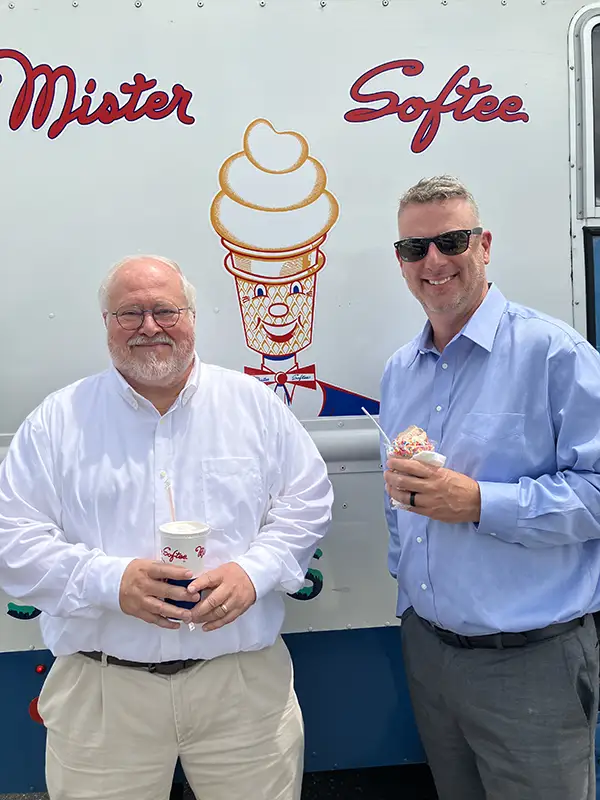 Two Elmer Bank representatives standing in front of Mr. Softee ice cream truck mascot.