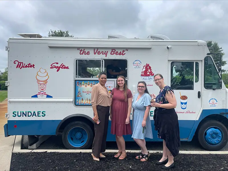 Four Elmer Bank employees posing in front of a Mr. Softee ice cream truck.