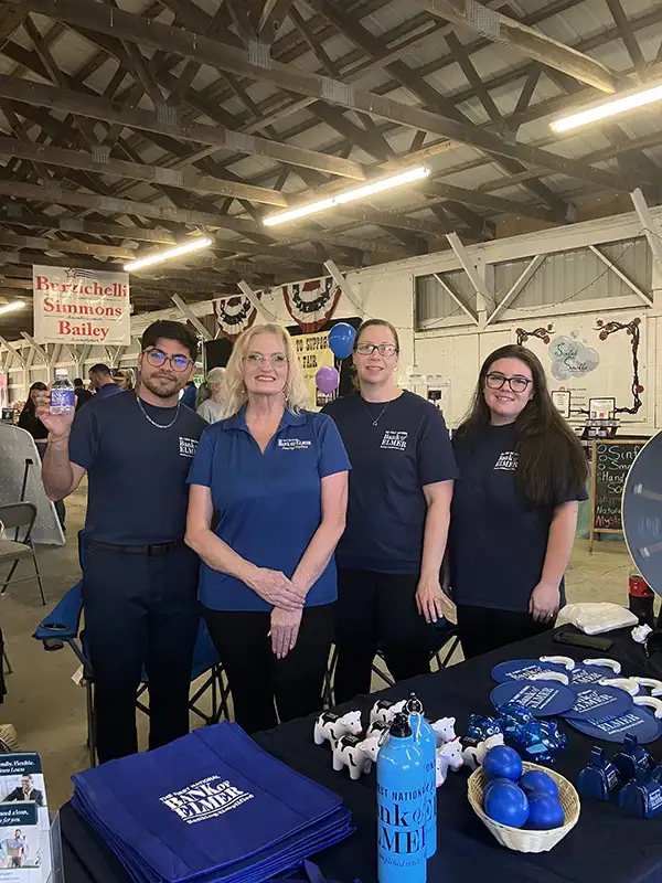 Four Elmer Bank employees posing at the Elmer Bank table.
