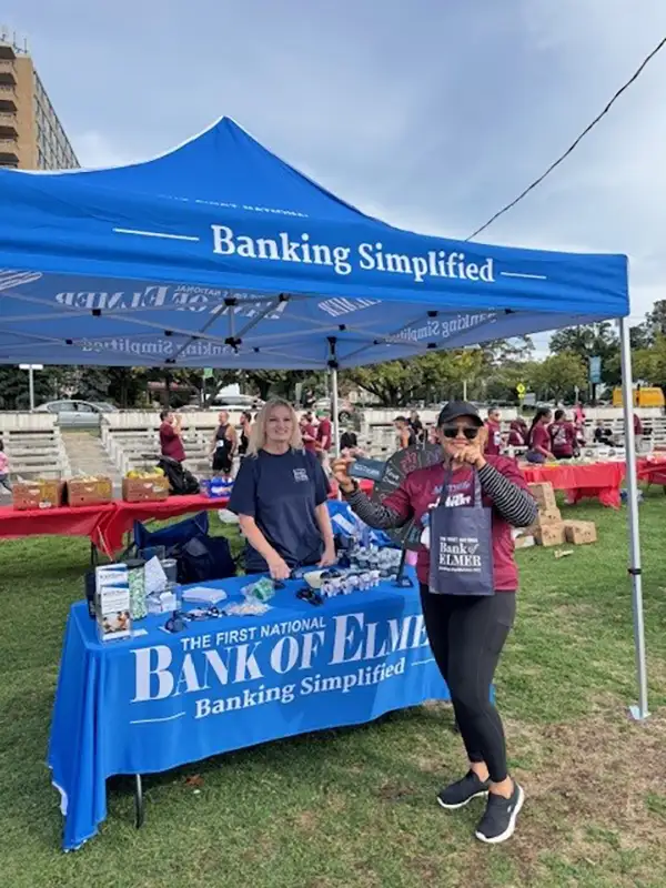 Elmer bank employee at booth with someone presenting Elmer Bank gear