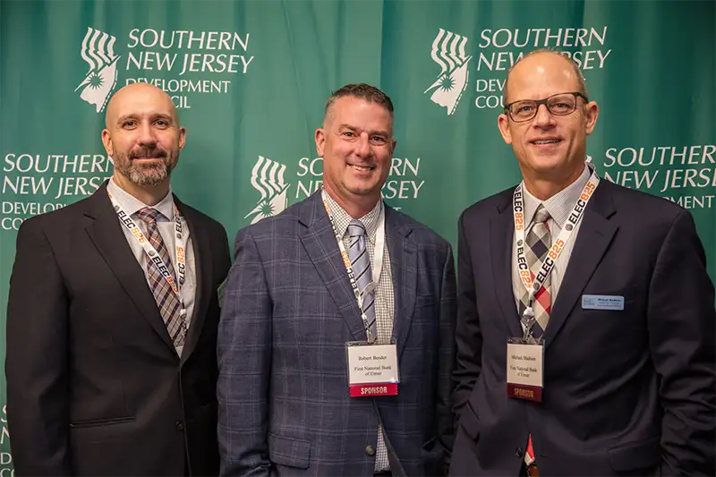 Three men posing for a picture against green backgrounds