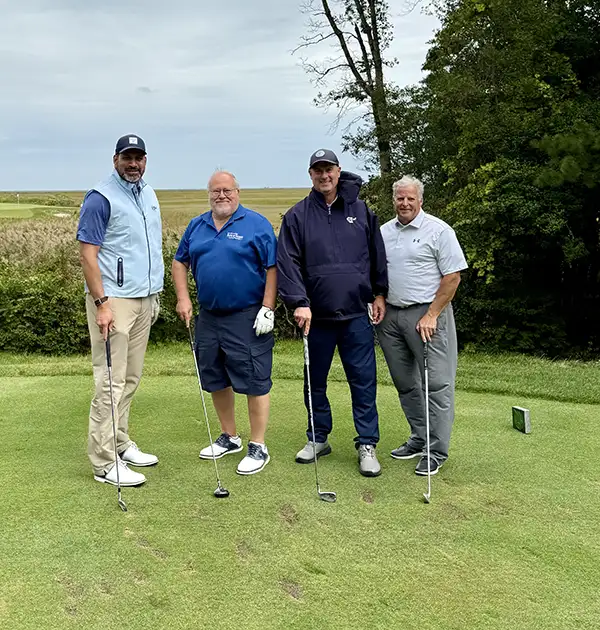 Four men with golf clubs pose for a picture