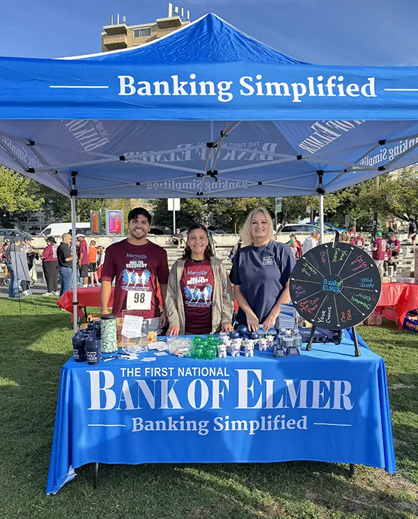 Three Elmer Bank employees under at the Elmer booth under the Elmer tent