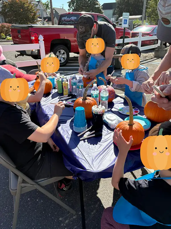 Group of kids and adults painting pumpkins.