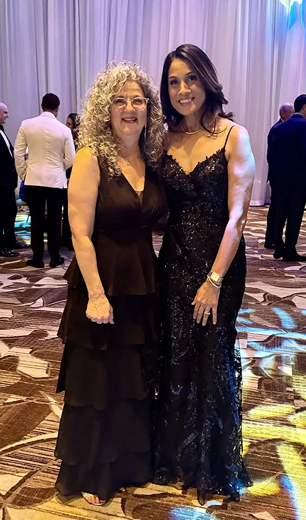Two women in black formal dressed posing at gala