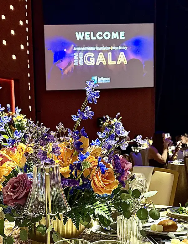 Color floral arrangement on table with Welcome to Gala message on screen in background